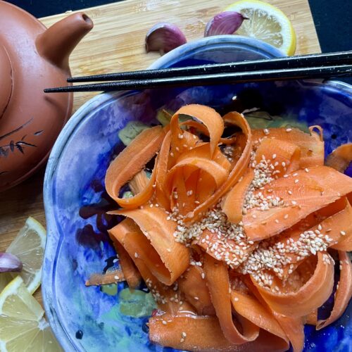 Close-up of Asian Roasted Sesame Oil Carrot Salad, showcasing vibrant, thinly sliced carrots glistening with a flavorful sesame dressing.