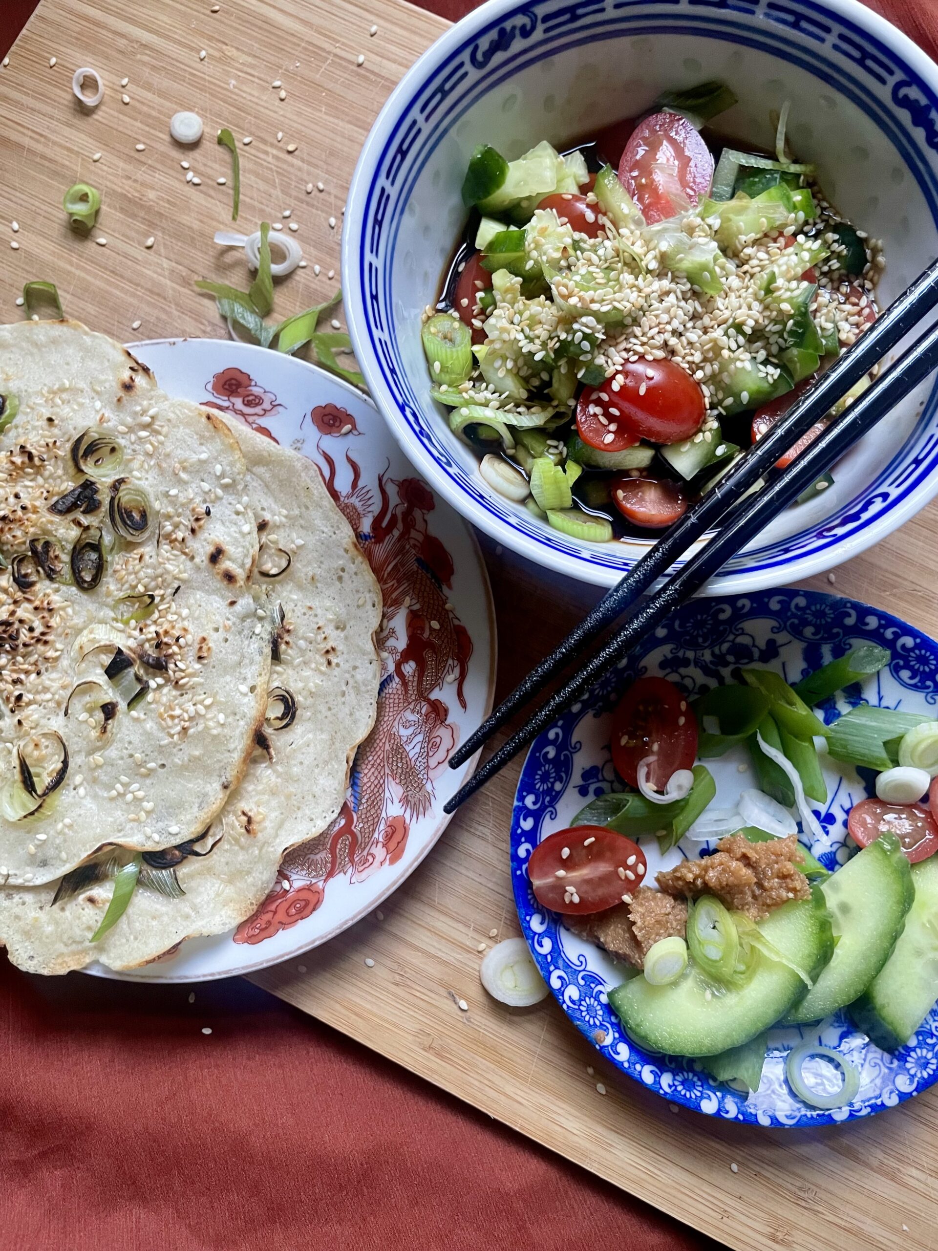 Delicious homemade savory pancake with crispy edges, topped with sesame seeds and served with a flavorful miso dipping sauce and a medley of chopped vegetables.