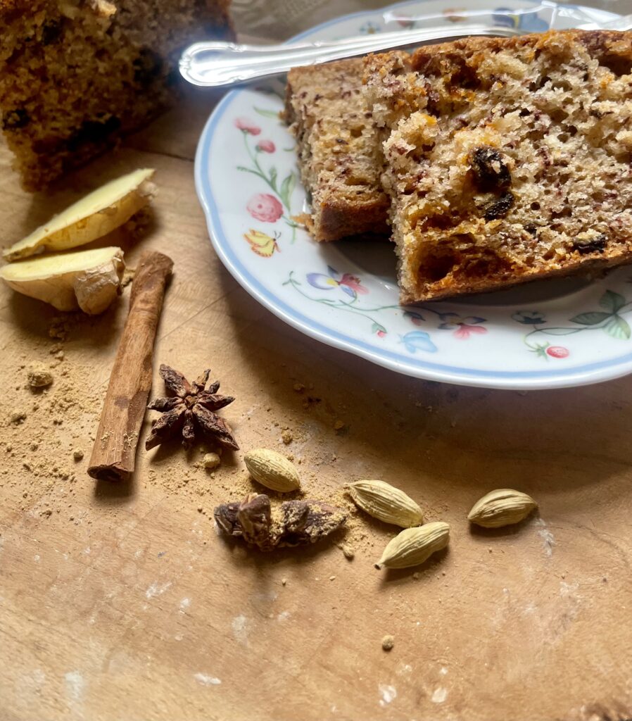 A close-up of aromatic spices—cinnamon, cardamom, and star anise—artfully scattered next to vegan cardamom sourdough banana bread, enhancing the visual appeal and hinting at the delightful flavors within.