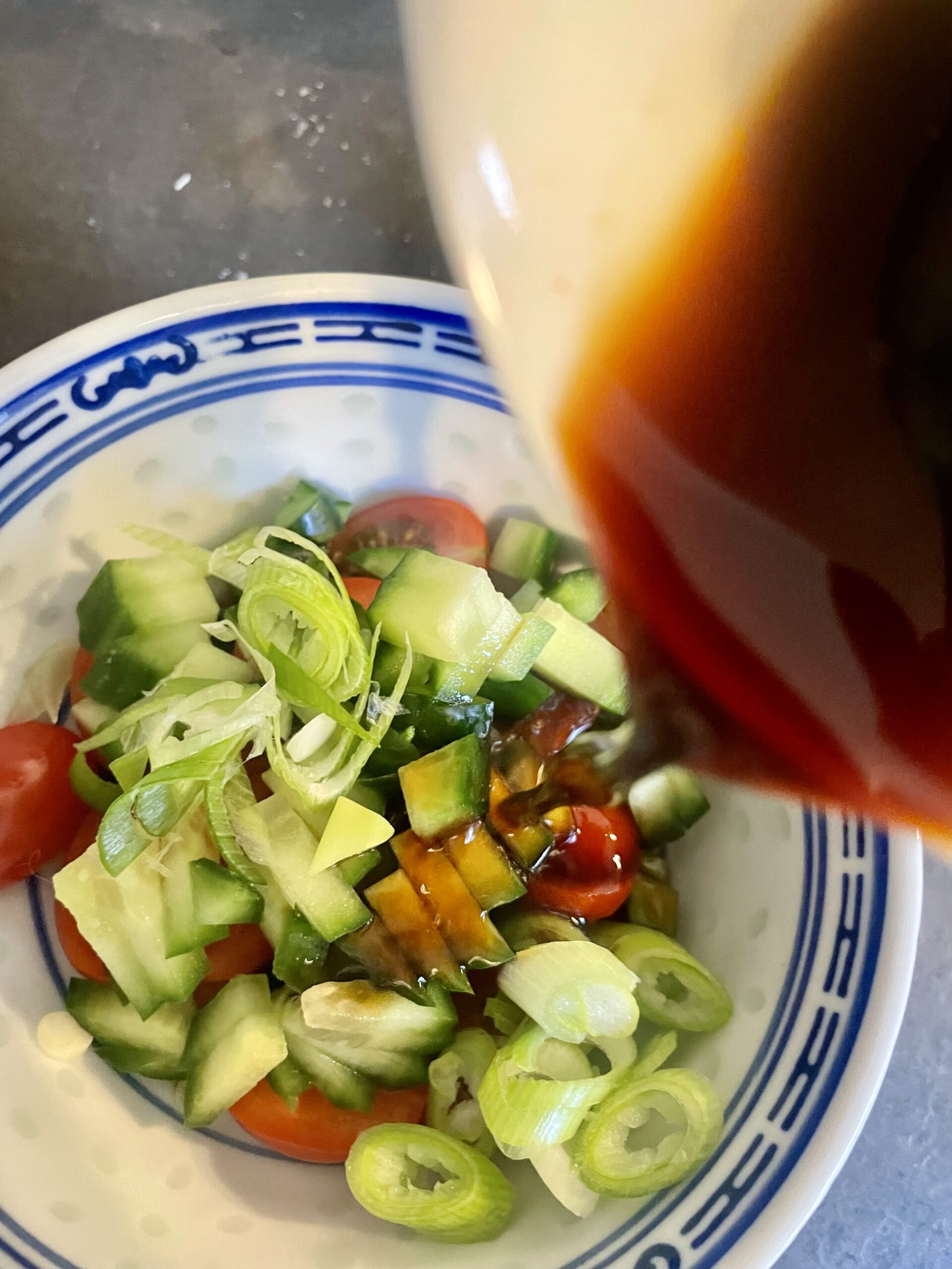 Capturing the moment: Pouring the flavorful soy-miso-dipping sauce over a colorful medley of cucumber, tomatoes, and spring onions. A vibrant and refreshing ensemble ready to elevate the savory sourdough discard pancakes.
