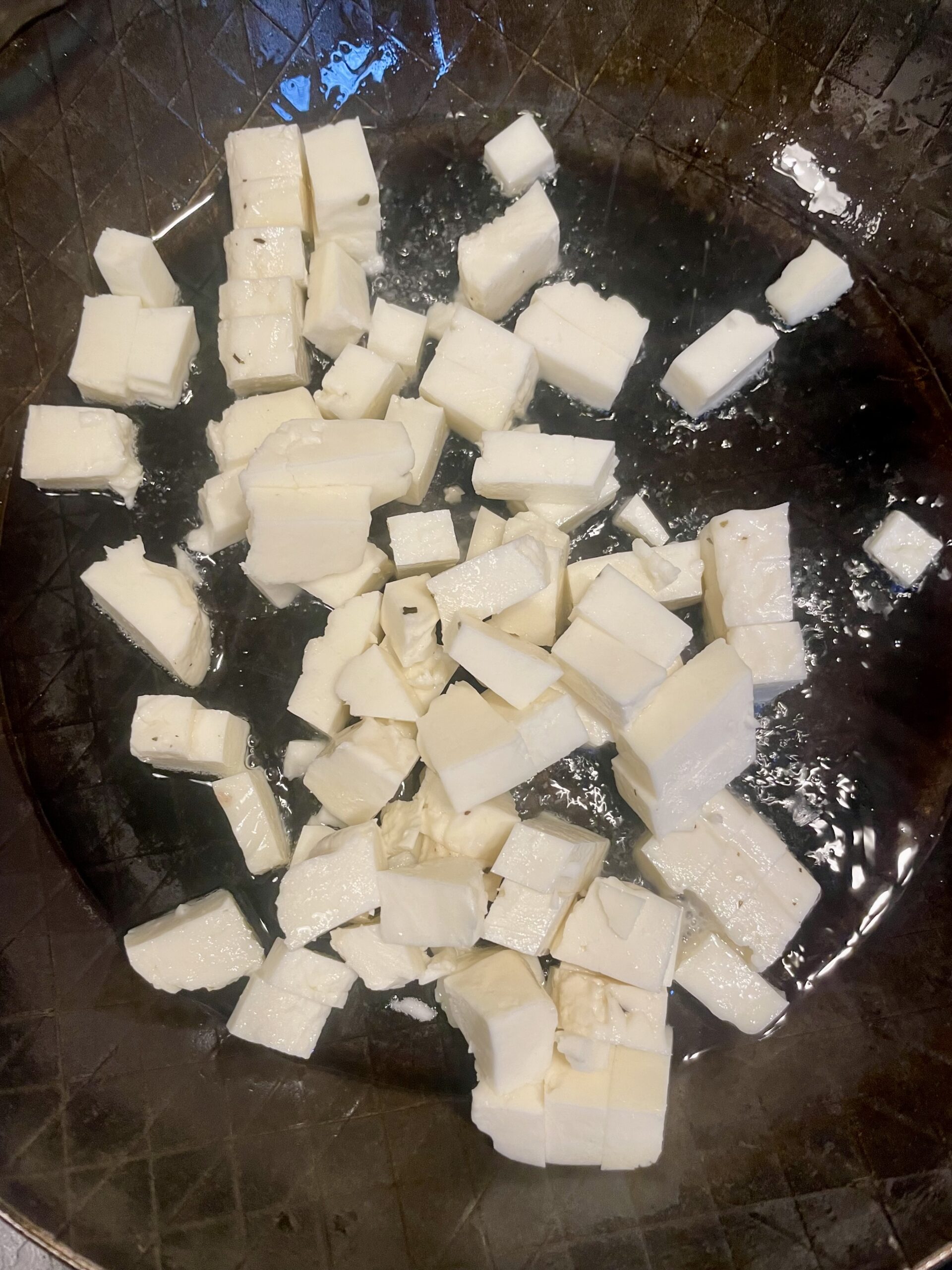 Halloumi sizzling in a hot skillet during the first step of Saag Halloumi with Kale preparation.