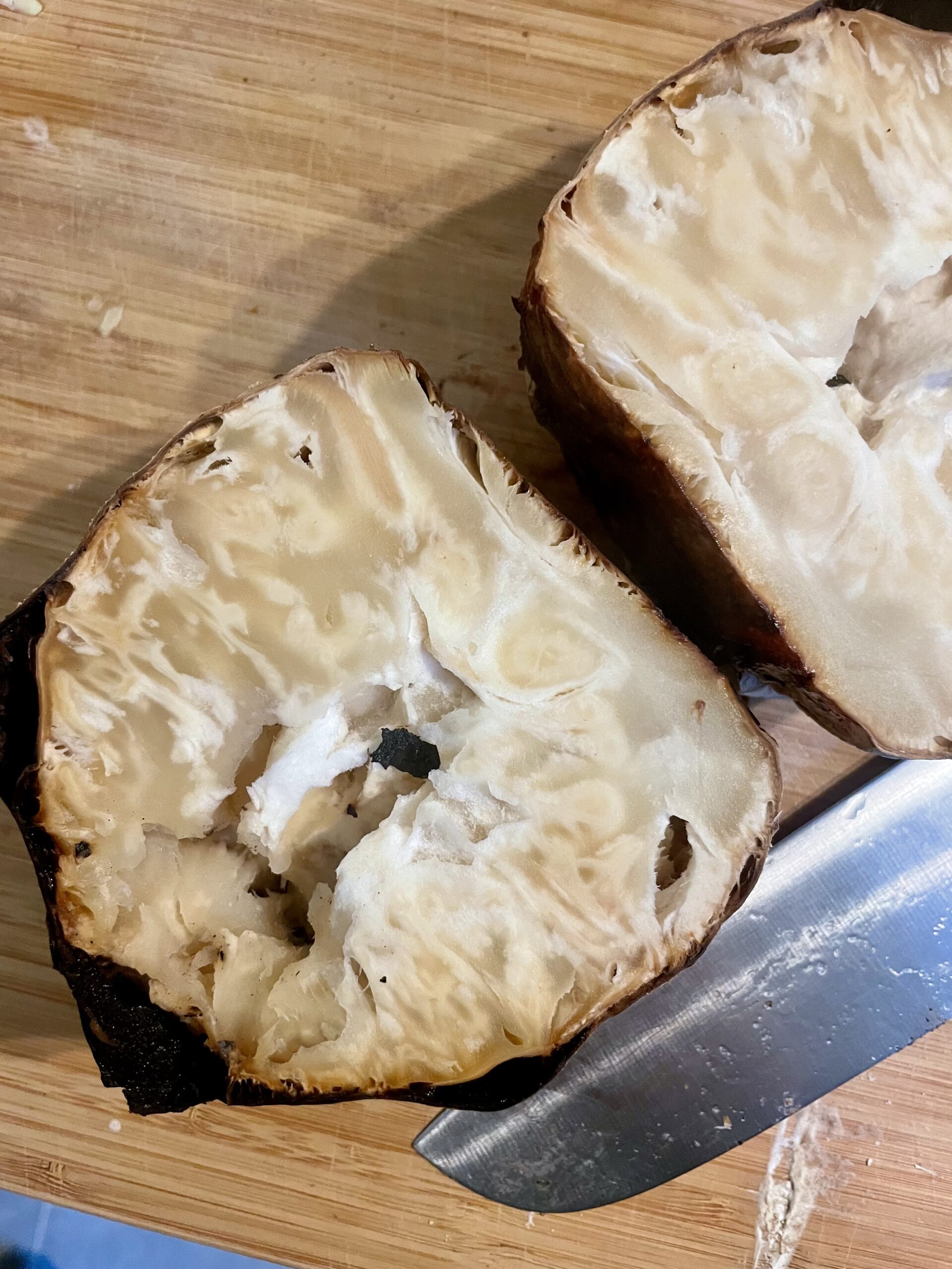 Perfectly Roasted Celery Root - Capturing the moment when the celery root emerges from the oven, perfectly cooked to a firm, potato-like consistency. Cut in half to reveal its ideal texture, this image sets the stage for our Asian Star Anise Roasted Celery Root (Vegan) recipe.