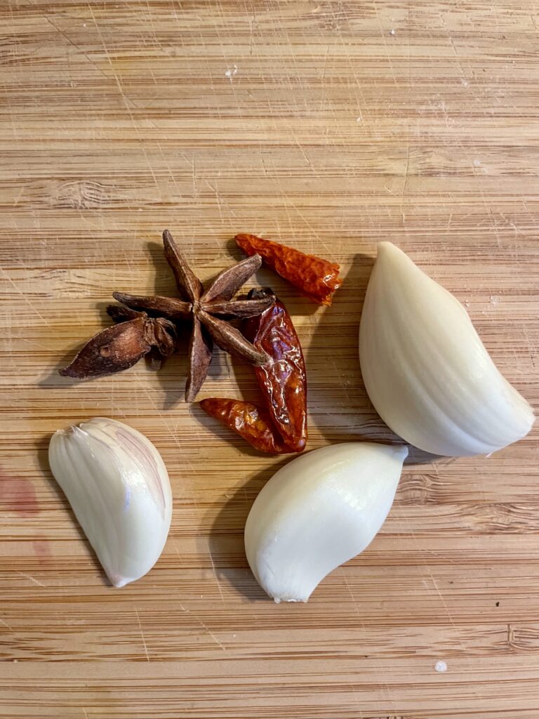 Flavorful Ingredients Lineup - A close-up showcasing the essential components of our Asian Star Anise Roasted Celery Root (Vegan) recipe: cloves of garlic, whole star anise, and an optional chili for those seeking a hint of heat. These aromatic elements promise to elevate your culinary experience.