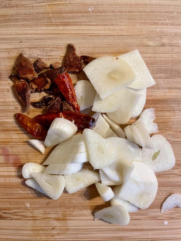 Aromatic Ingredients in the Spotlight - Witness the transformation: A close-up view of the garlic, star anise, and optional chili, finely chopped and ready to infuse their enticing aromas into sunflower oil for our Asian Star Anise Roasted Celery Root (Vegan) recipe.